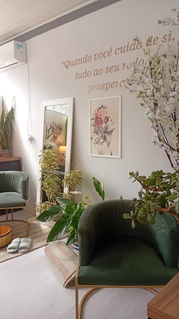 Parede da Nórtus com a frase “Quando você cuida de si, tudo ao seu redor prospera”, poltronas verdes e plantas