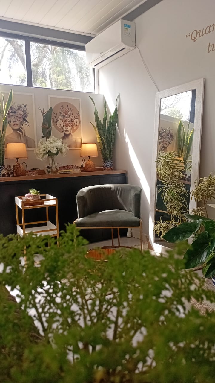 Espaço de recepção da Nórtus com poltrona verde, espelho, plantas e luminárias de luz quente